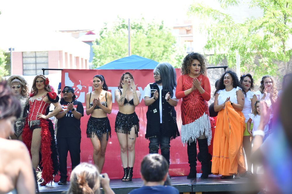 A group of diverse Latine performs clap and smile at a cheering crowd.