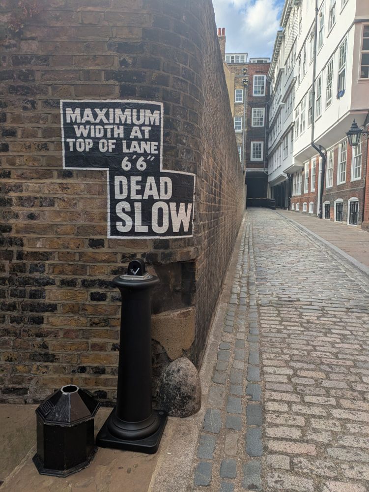 A painted 'maximum width' sign on a brick wall