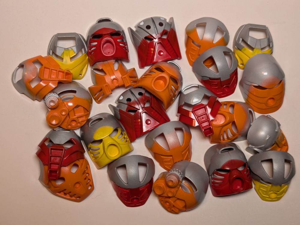 A collection of Great and Noble Kanohi in red, orange, and yellow. All of them have the top blended with silver