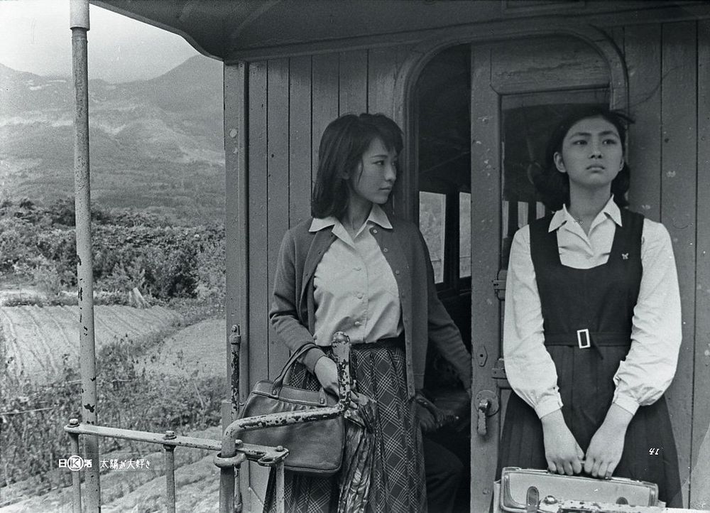 Meiko and Izuni standing at what looks like the back end of a train car