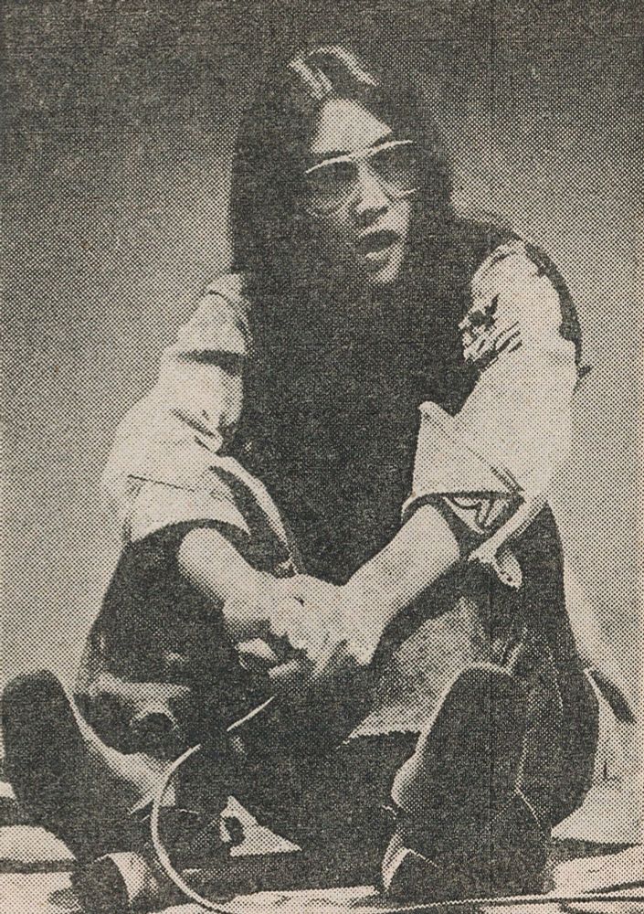 Black and white image of Meiko sitting down. She's wearing sunglasses and looks to be yawning?