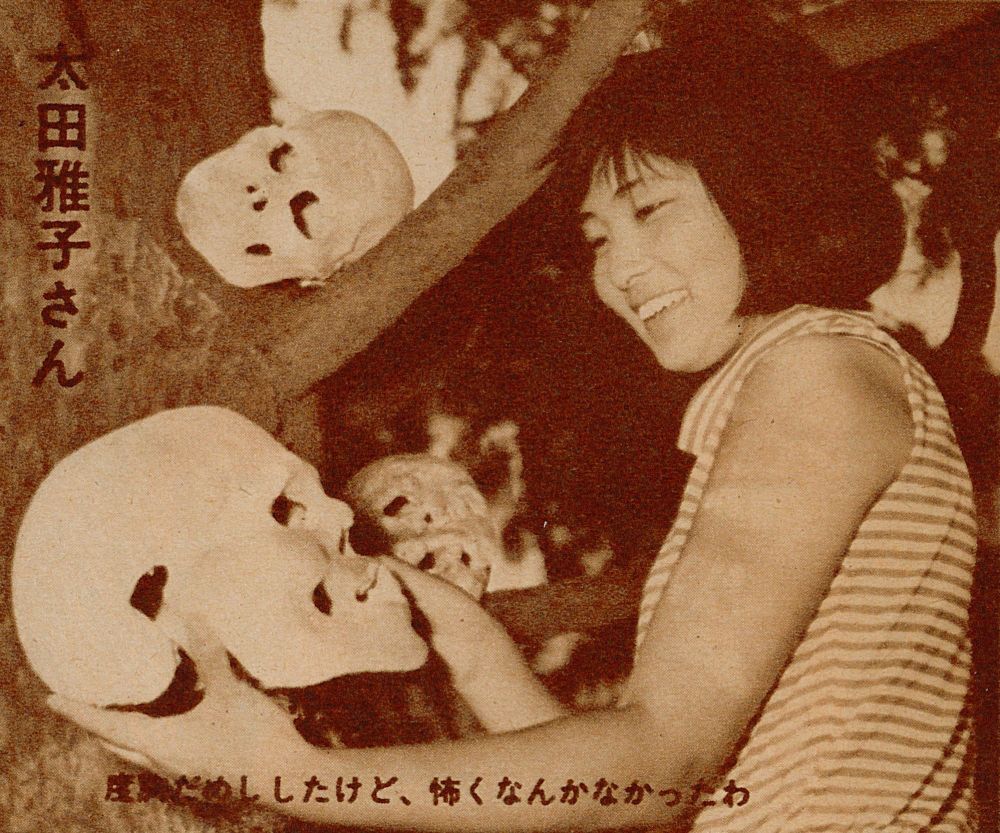 Mid-shot of a very young Meiko holding a fake skull in her and and smiling at it