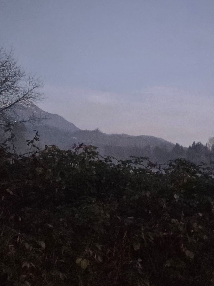 Mountain peeking out from foothills on a foggy morning. Almost blue sky. 