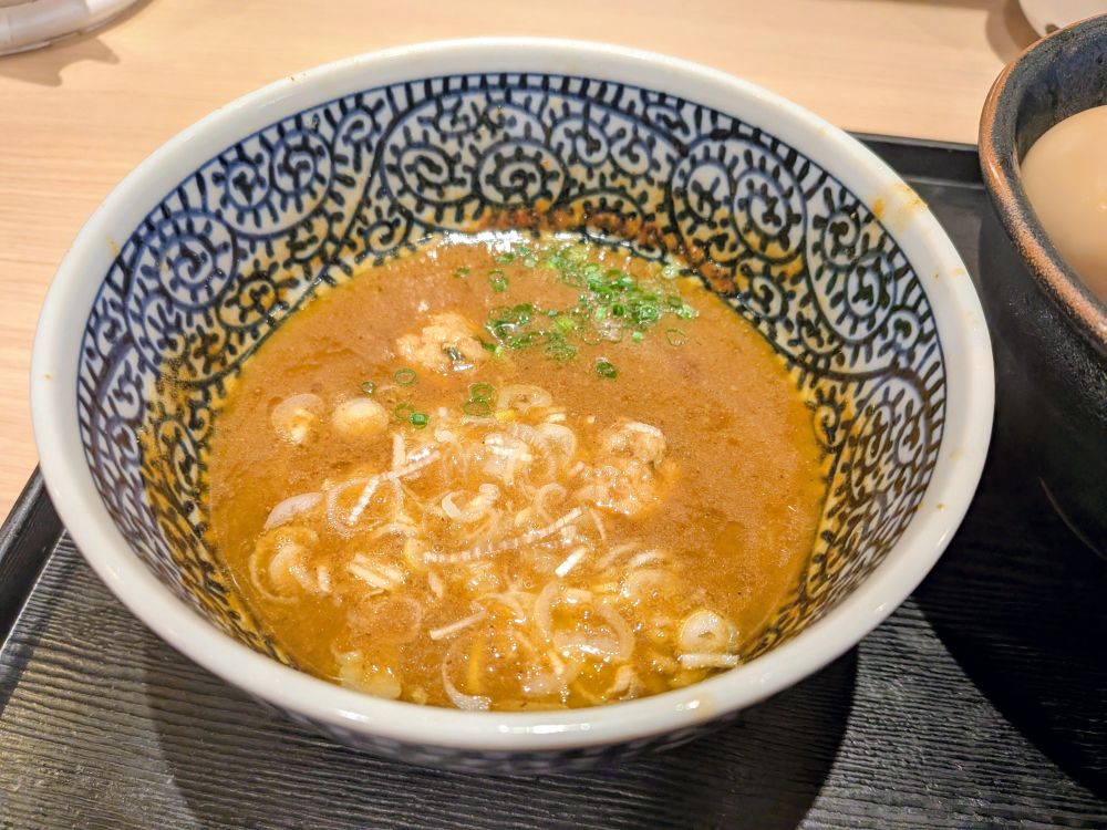 도쿄 신코이와 '멘야 잇토'의 특제 츠케멘. 면과 토핑을 넣어 먹는 밝은 갈색의 스프입니다. 가늘게 썬 파가 들어 있는 게 보입니다.