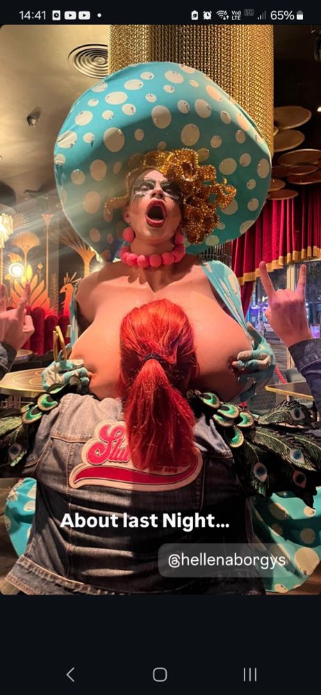 Drag queen posa com fã entre suas proteses falsas .