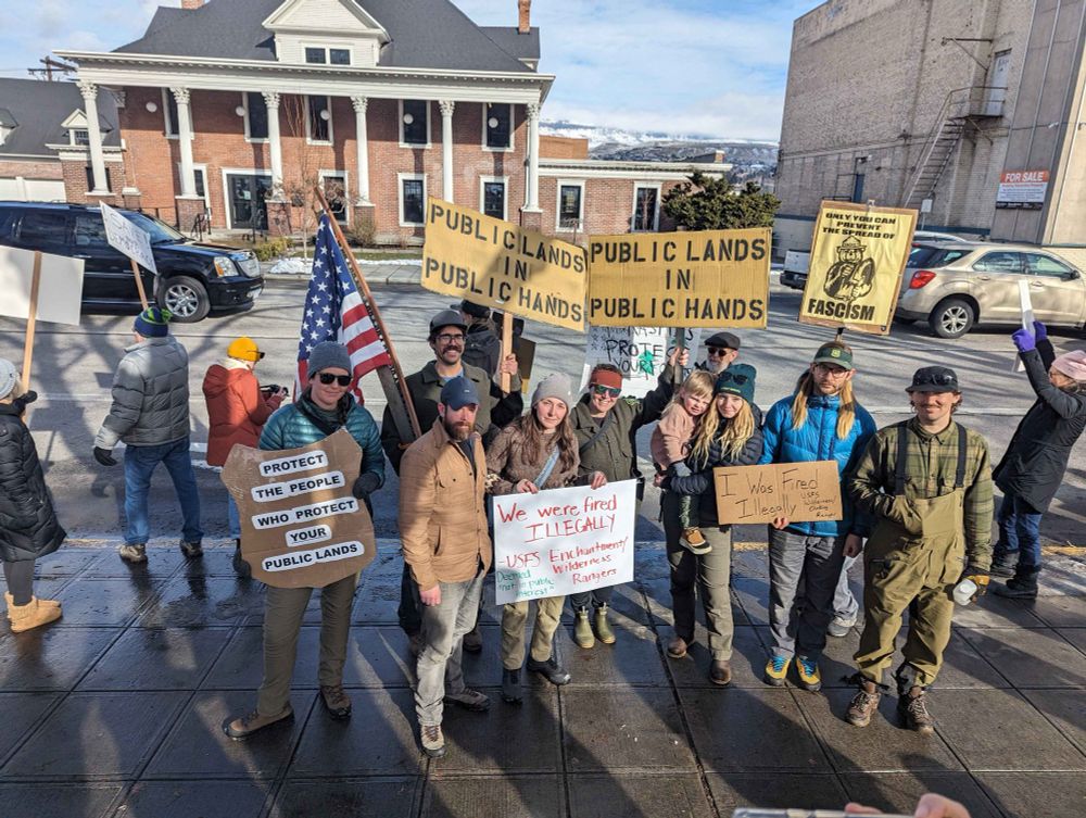 Forest service employees at a demonstration are holding signs protesting  illegal firings of federal workers. 