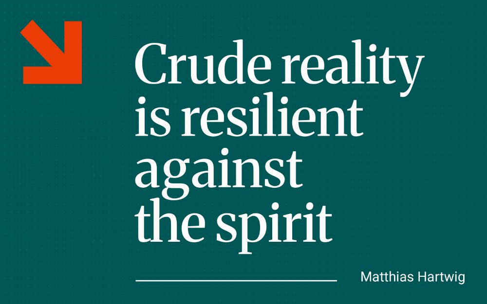 Graphic featuring a quote from Matthias Hartwig's text on a teal background with a bold orange arrow symbol in the top left. To the right, large white serif text reads: ‘Crude reality is resilient against the spirit’. Beneath the quote, in smaller white text aligned to the right, is the attribution: ‘Matthias Hartwig’.