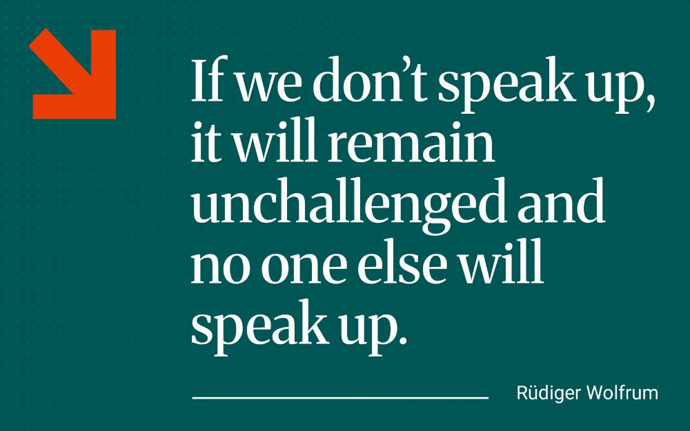 Graphic featuring a quote from Silja Vöneky's text on a green background with a bold orange arrow symbol in the top left. To the right, large white serif text reads: ‘If we don't speak uo, it will remain unchallenged and no one else will speak up.’. Beneath the quote, in smaller white text aligned to the right, is the attribution: ‘Rüdiger Wolfrum’.