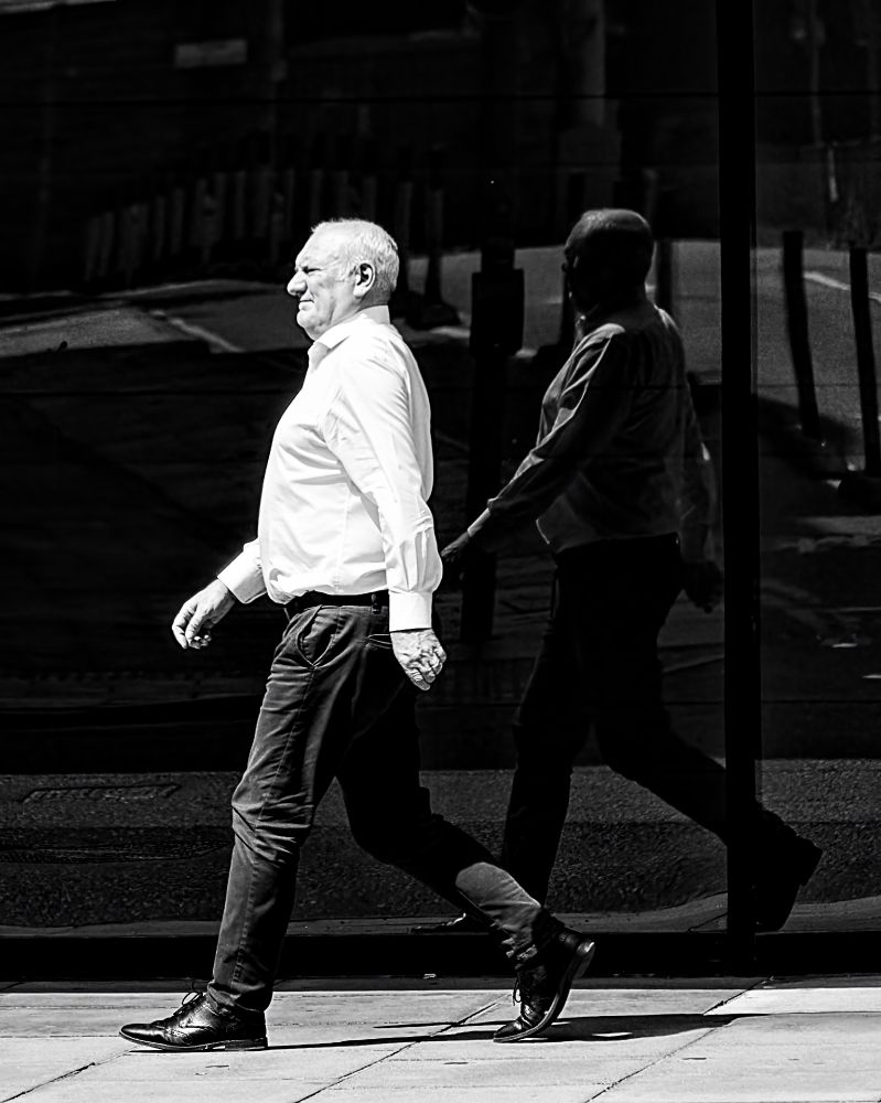 A man walks by a dark window, on a sunny day, and is reflected in it. Semple Street, Edinburgh