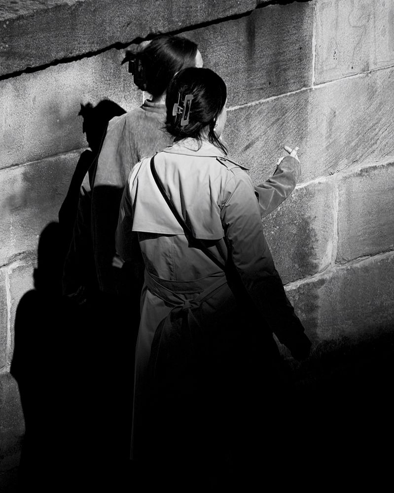 Two women walk along Market Street, Edinburgh, half in shade, half in the sun