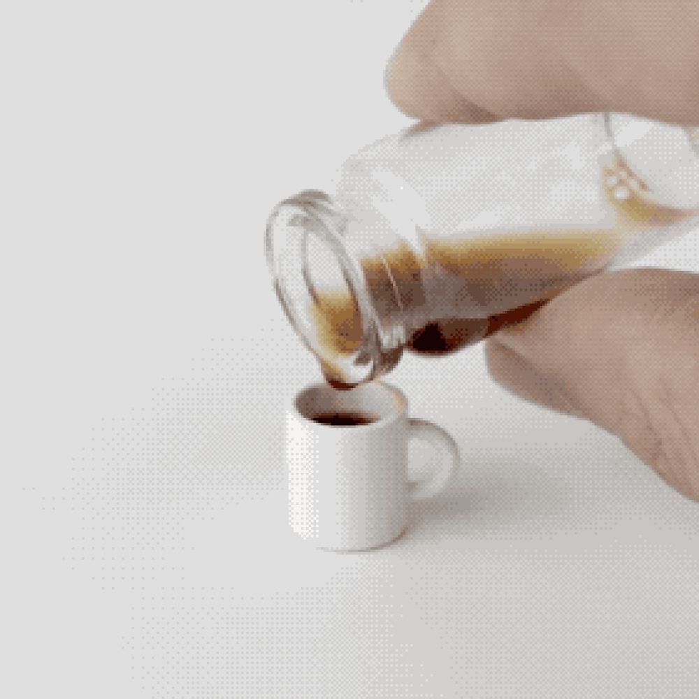 In eine Kaffeetasse, die ungefähr so groß ist wie ein Daumennagel, wird ein Tröpfchen Kaffee eingegossen. 