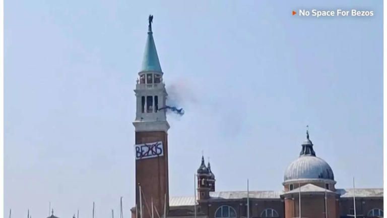 bell tower rising over a domed church, there's a banner with the word BEZOS crossed out in red. blue smoke comes from the tower

it's san giorgo in venice