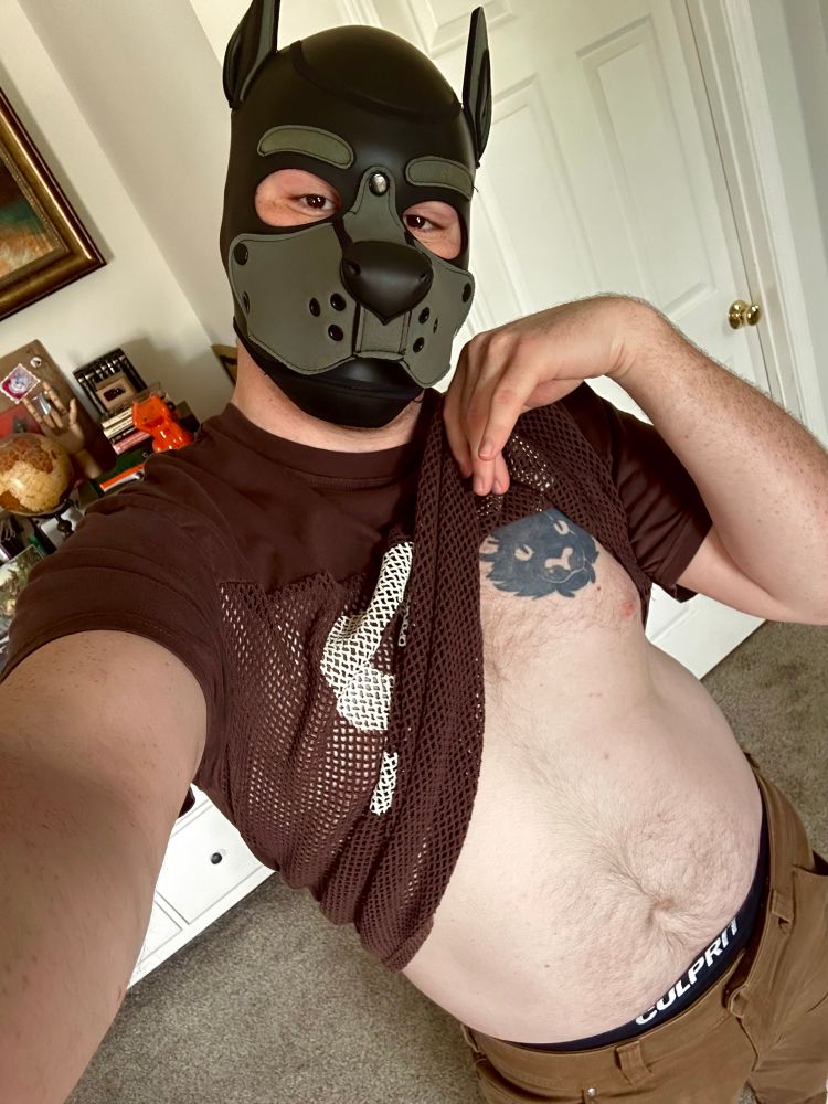 a man in a dog mask holding his sports jersey up at his chest and taking a selfie