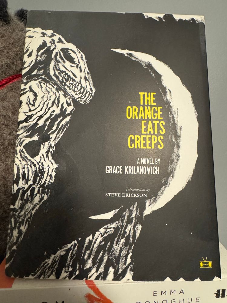 Paperback cover of Grace Krilanovich’s The Orange Eats Creeps. Black cover featuring a moon, yellow lettering on the title and skeleton lizard monsters.
