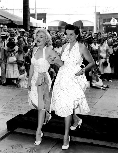 OK it's actually Marilyn Monroe and Jane Russell stepping off the dais, arm in arm, at Grauman's Chinese for their footprint ceremony in 1953. They both have on halter dresses with polka dots and very high white heels.
