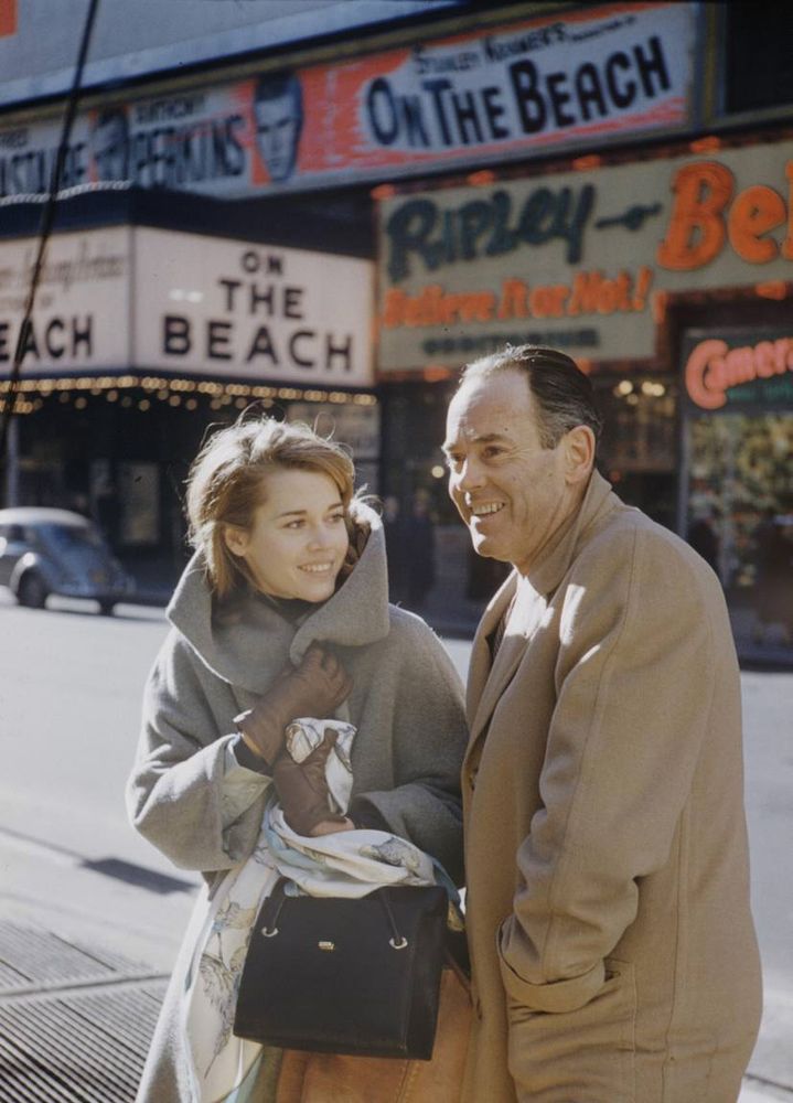 Cold-weather shot; both Jane and Henry are in wool coats; a marquee for ON THE BEACH is visible in the background
