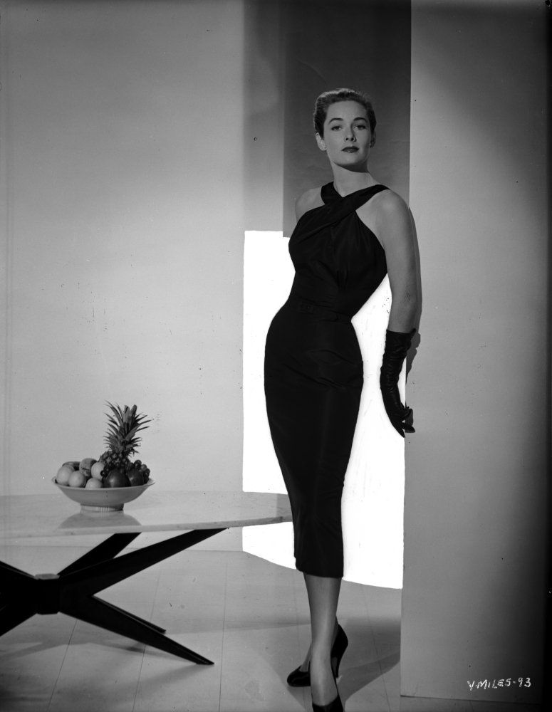 Vera Miles posed standing in a black, ankle-length halter dress and mid-length black gloves. 
