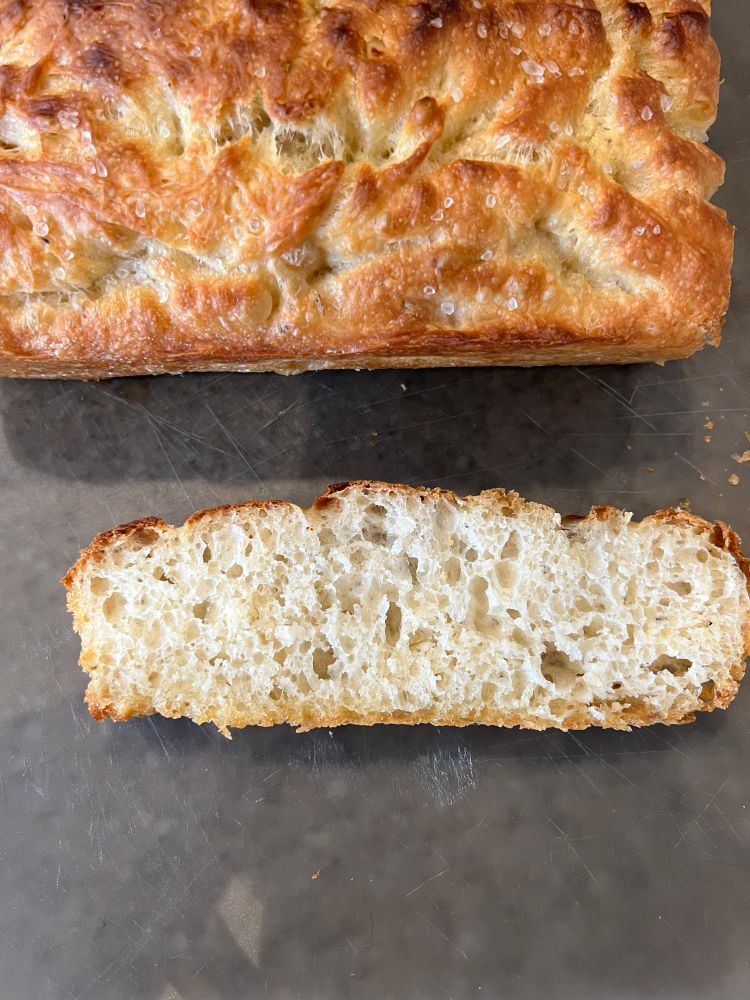 Slice of bread with focaccia behind. 