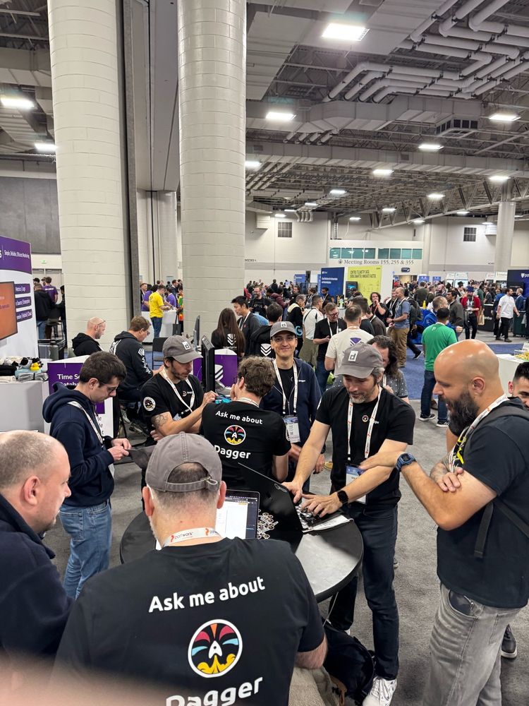 Dagger booth at KubeCon with many people wearing containerd hats