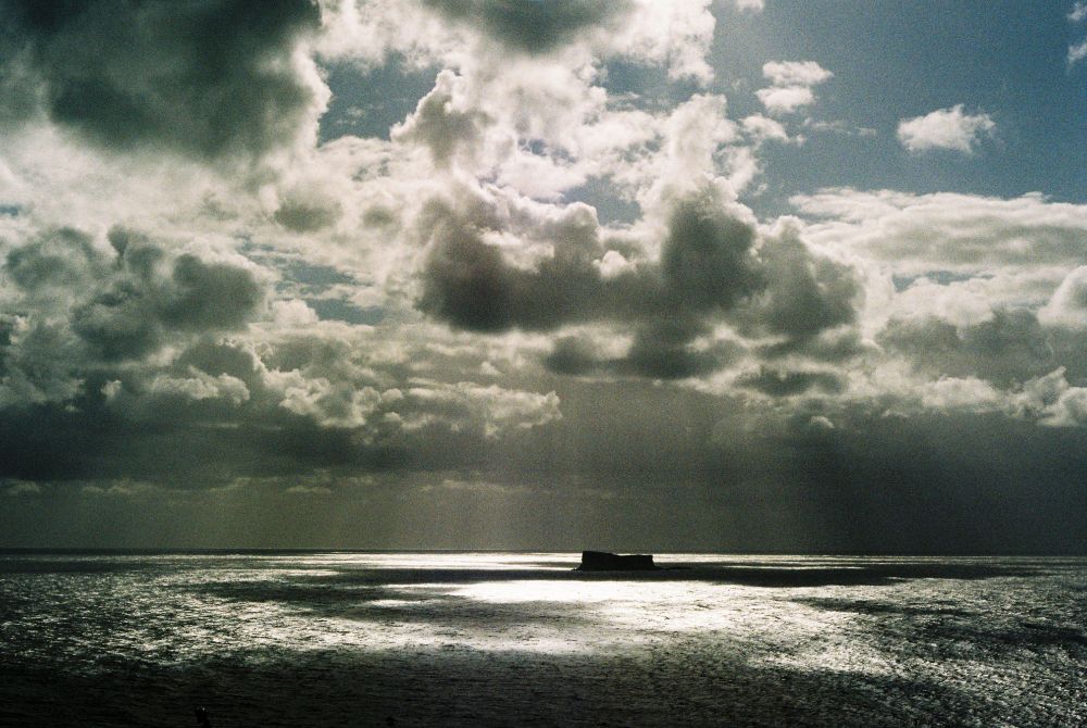 Crepuscular rays breaking through clouds over Filfa island off the coast of Malta, with dramatic shadows cast over the Mediterranean. Shot with a Leica M6 rangefinder camera on Kodak Gold 200 35mm film