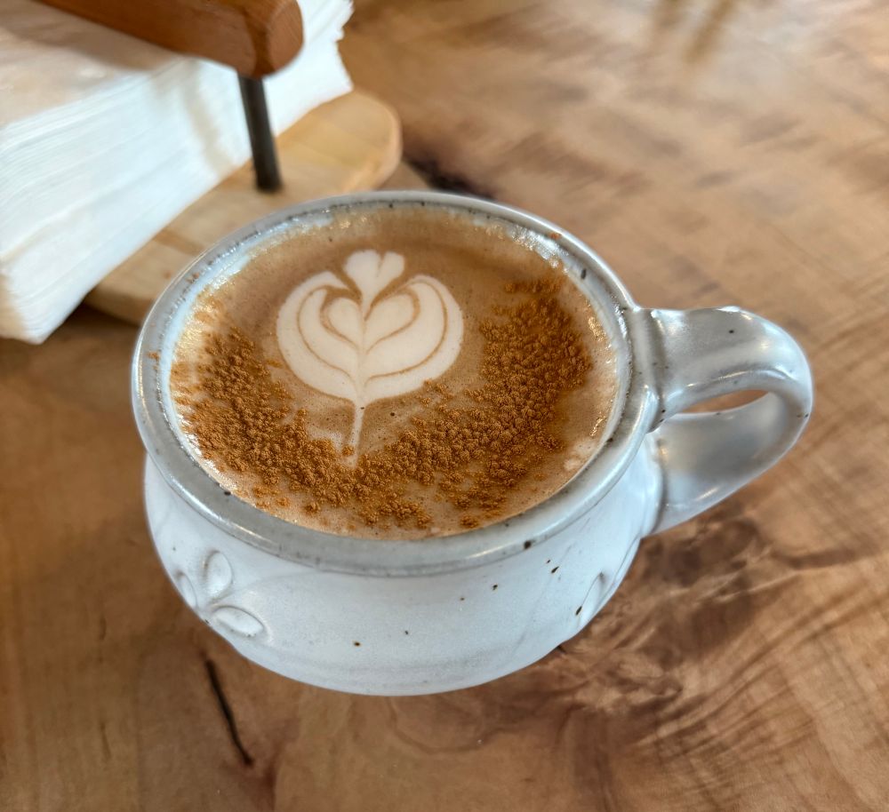 A cup of chai latte sprinkled with cinnamon, with a heart made out of froth.