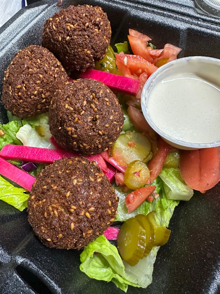 Falafel & tahini sauce over mixed veggies & pickles