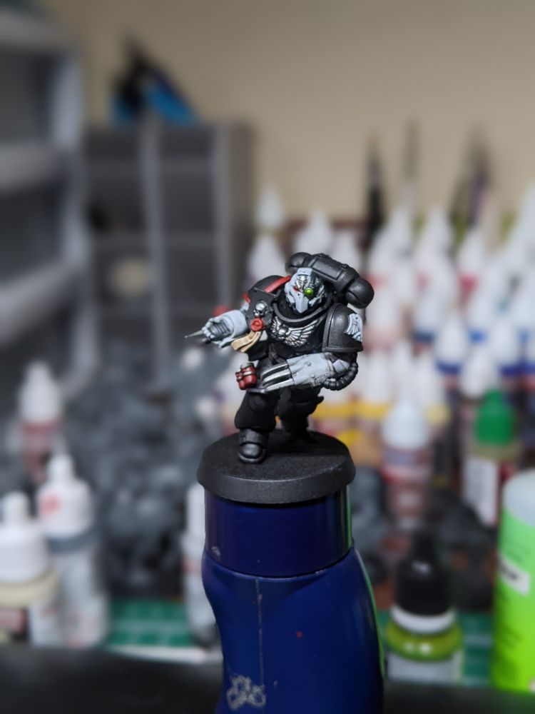 A space marine charging on foot in black armor. His weapons are shiny metal claws at the end of white power armor arms. 