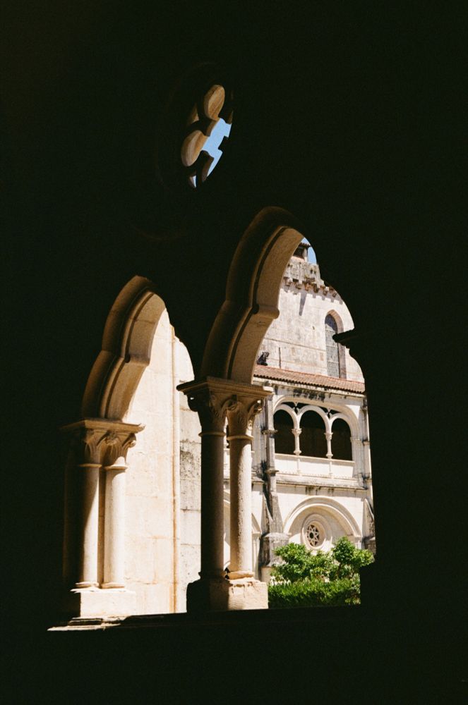 A dark archway with a bright church cloister shining through. 
