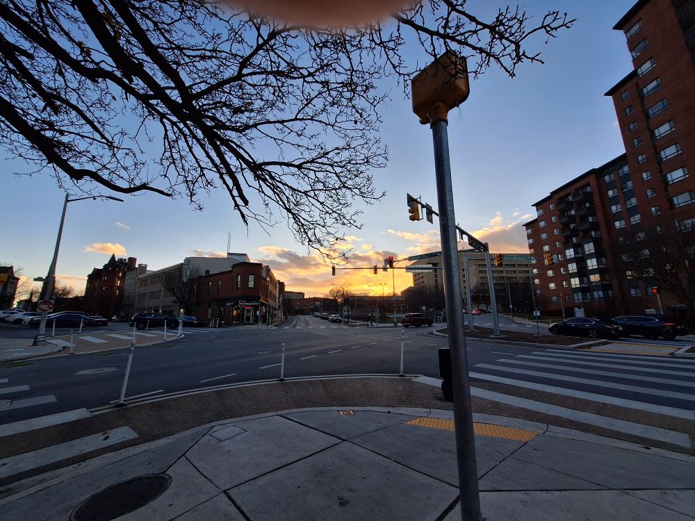 A fiery sunset, bright yellow clouds reflecting a sun we can't actually see anymore, but there are rays visible and intense light between two busy streets and then a bright blue simple, cloudless sky everywhere else.  

This version of the shot has a winter tree, walk signal and big crosswalks in the view.  