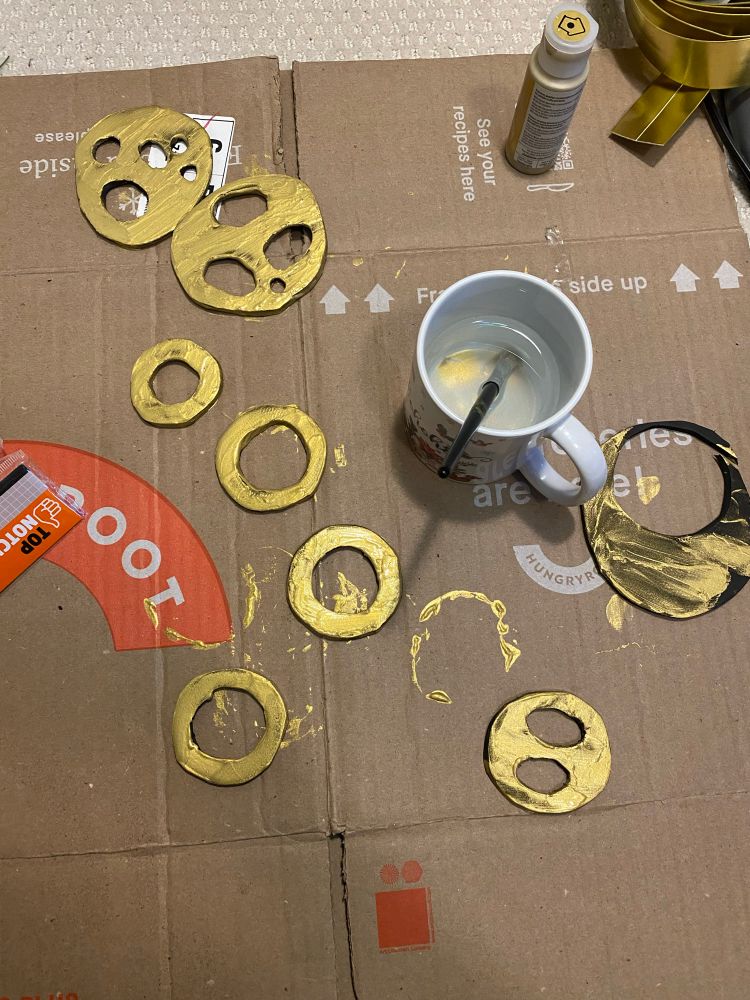 Foam rings painted gold sitting on top of cardboard 
