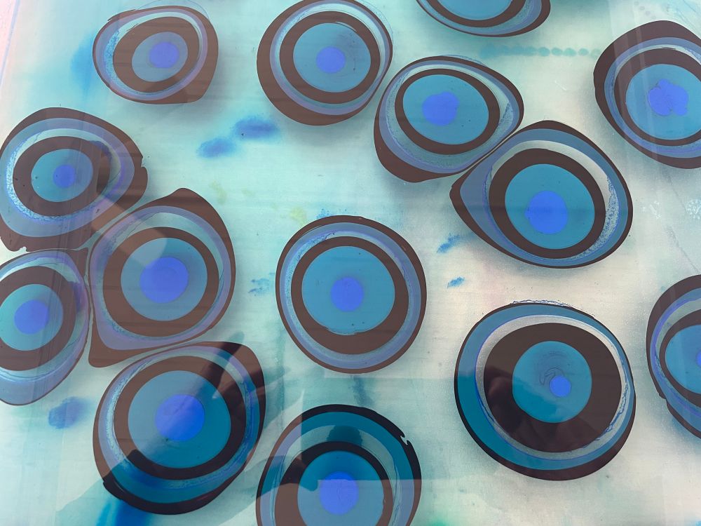 Concentric circle patterns of blue, green, and black paint are floating on top of the marbling “size” made of carrageenan (seaweed) and water