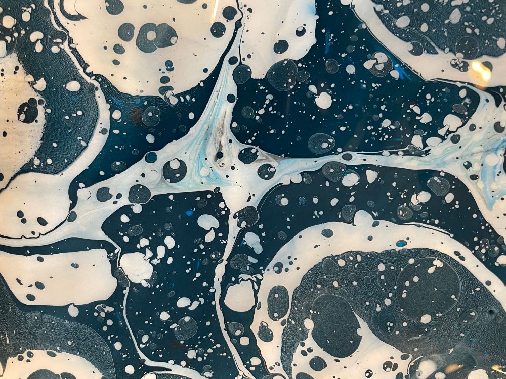 Detail of swirly, splotchy patterns of ink on a handmade marbled sheet of paper