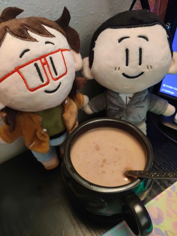coffee cauldron, now with creamer and cinnamon, sitting in front of the ryan and min-gi plushies looking like they're holding hands.