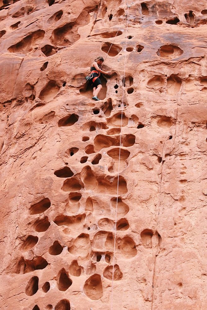 A woman climbing huecos.  These are big enough to stand in, and are super fun formations to climb!