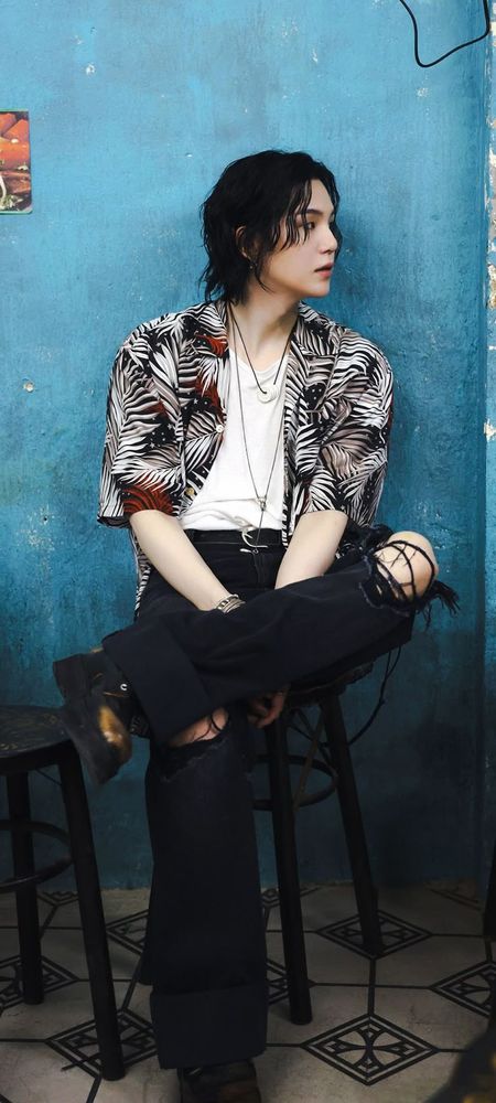 Image of thief Yoongi from Haegum MV sitting on a stool, looking fairly nonchalant with his sexy knee poking out of his pants.  