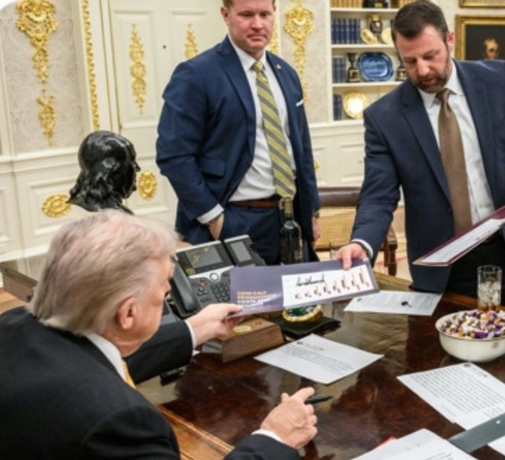 Trump handing an autographed document back to Senator Markwayne Mullin in the Oval Office as some other guy looks on 