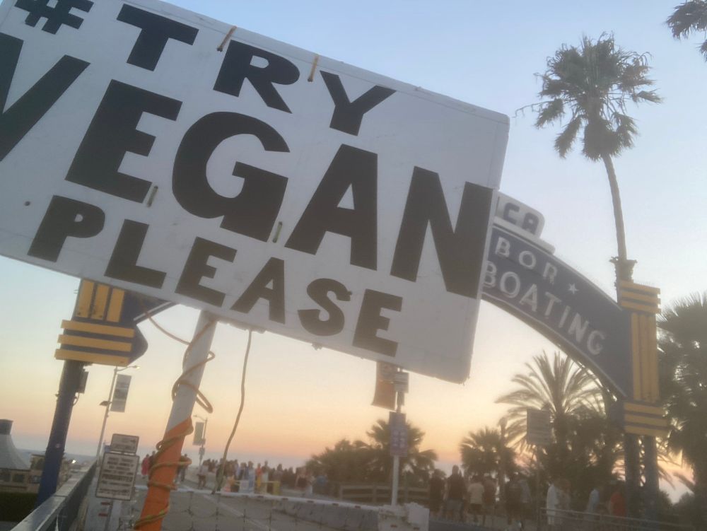 Try Vegan Please sign in front of the Santa Monica sport fishing sign