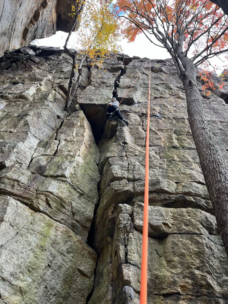 Me rock climbing. Orange rope running up from the bottom of the photo 