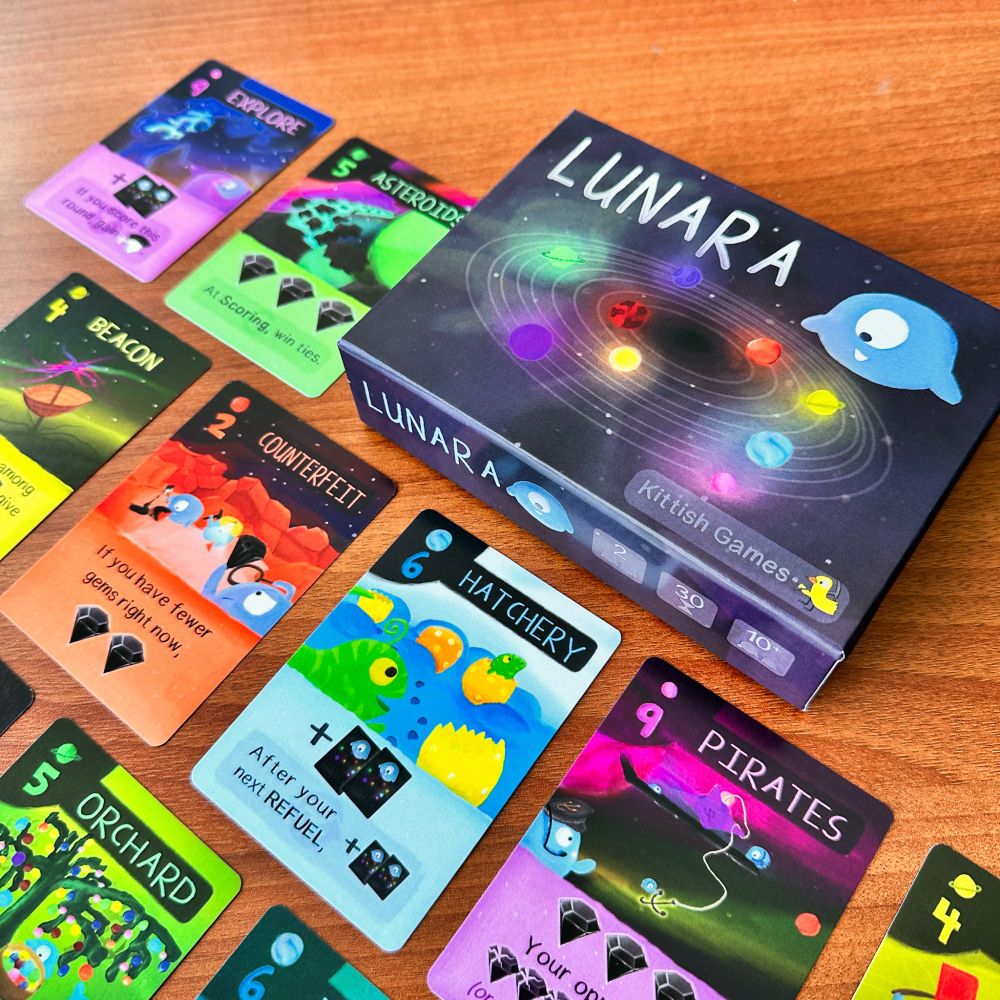 Board game and cards featuring little colroful space character cartoons
