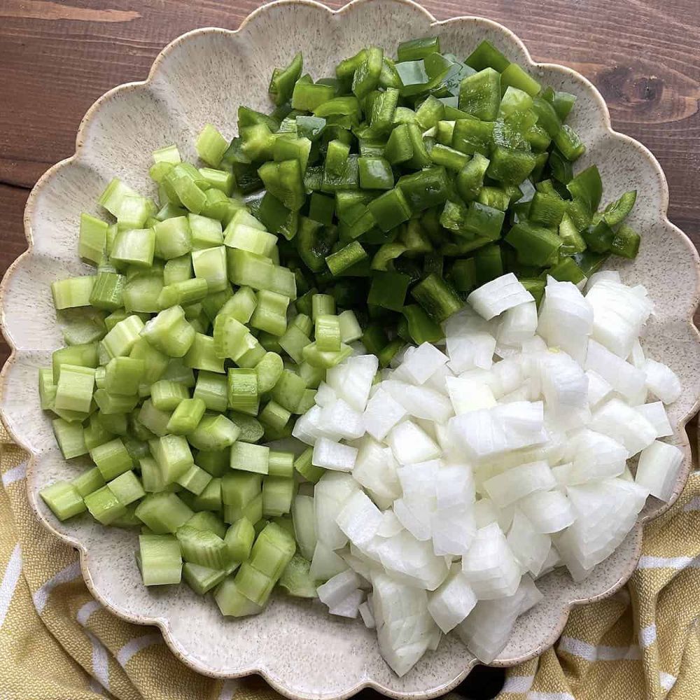 A photo of a bowl with chopped white onion, celery, and bell pepper, known as the Trinity of cajun cooking.