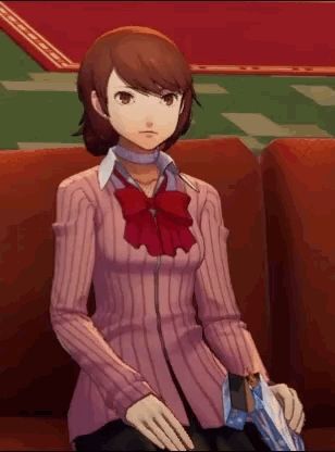 a girl in a pink sweater and red bow tie is sitting on a red couch .