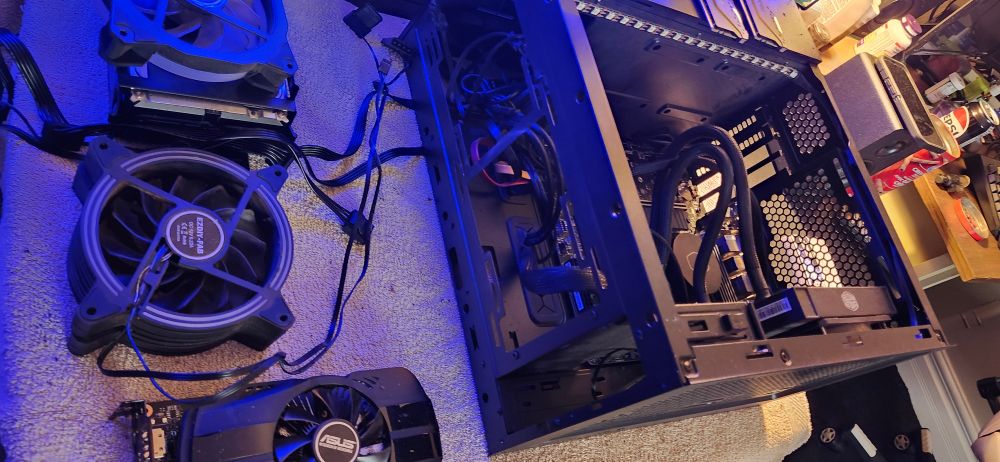 Opened and disassembled computer tower with fans and hard drives sitting nearby