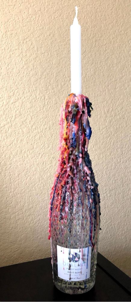 Vinflaske med stearinlys oppi, masse varm stearin har rent nedover flasken og stivnet