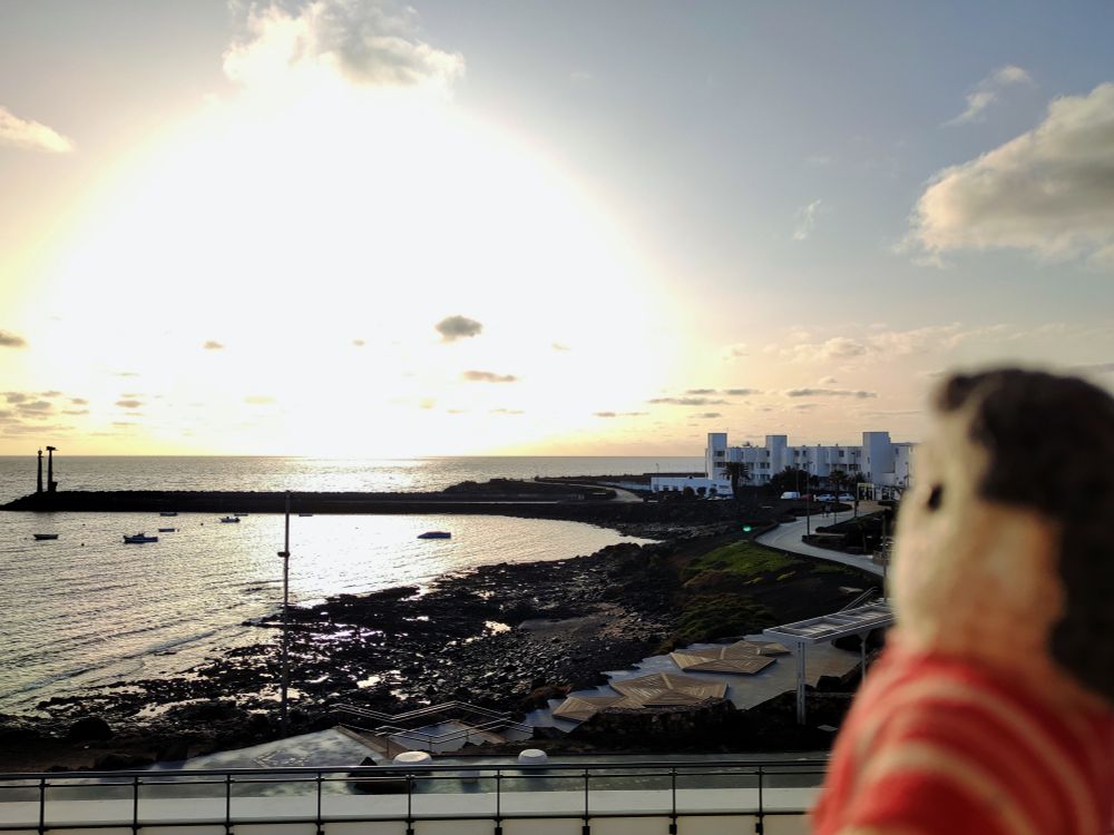 Crochet Tiny Nye in front of a stunning sunrise over the sea.