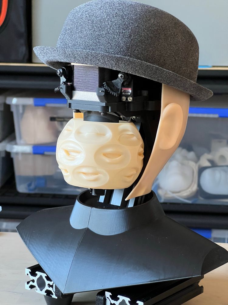 A picture of an animatronic head with its face removed. It’s wearing a hat, and its ears and the back of its head are fine, but the face is now just a big ball of mouths. 