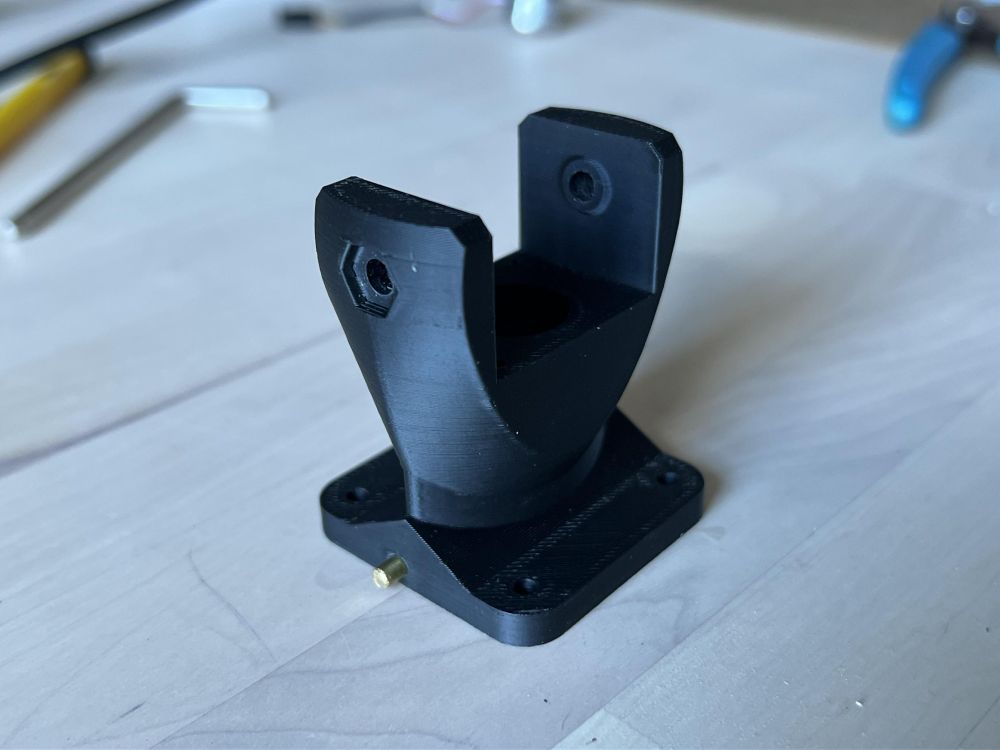 A 3D printed black plastic bracket, made up of simple curves and angles.