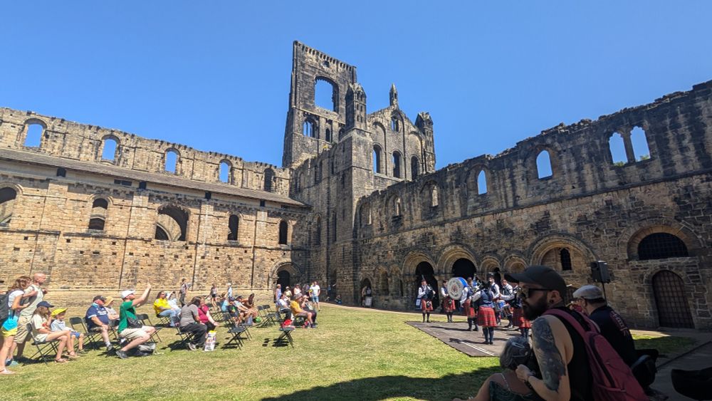 A view from the old cloisters, showing a grass-filled courtyard and the old walls and tower.