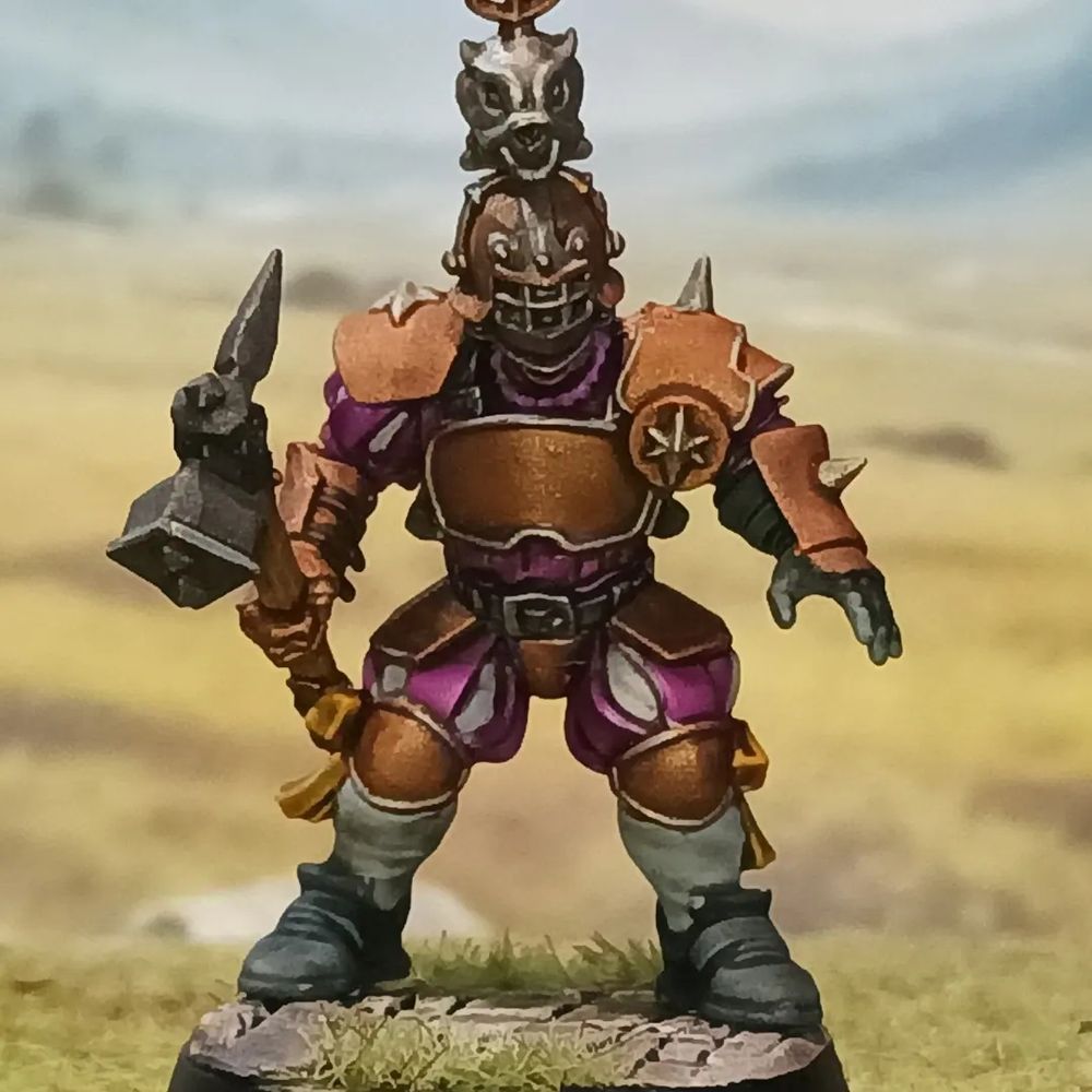 A warrior in heavy bronze armor and purple clothes weilding a hammer.