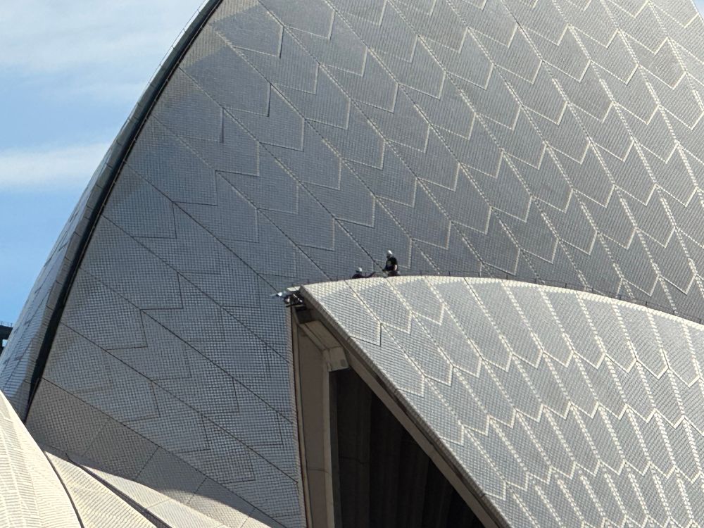 Two people climbing on the roof of Sydney opera house 