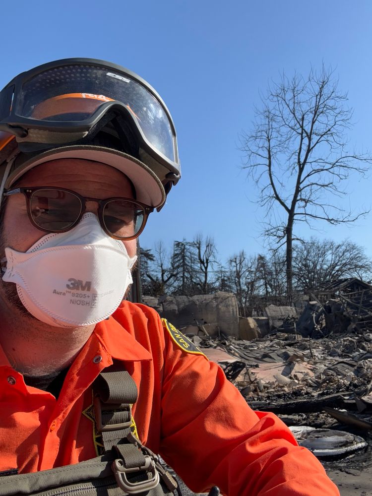 Yours truly in search and rescue field uniform with PPE in front of a severely fire-damaged home
